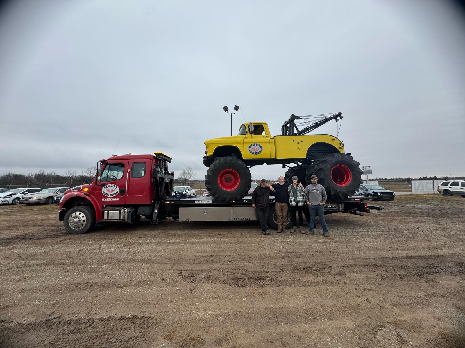 Brown & Sons flatbed tow truck carrying a vintage wrecker truck, with crew members in front