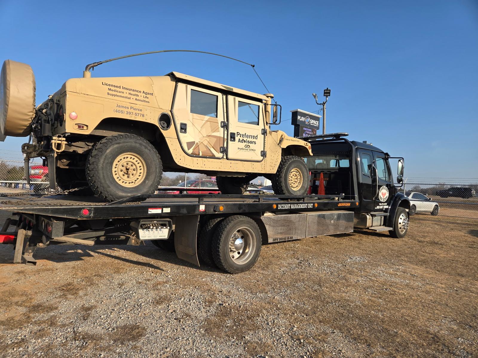 Brown & Sons rollback flatbed hauling a military Humvee