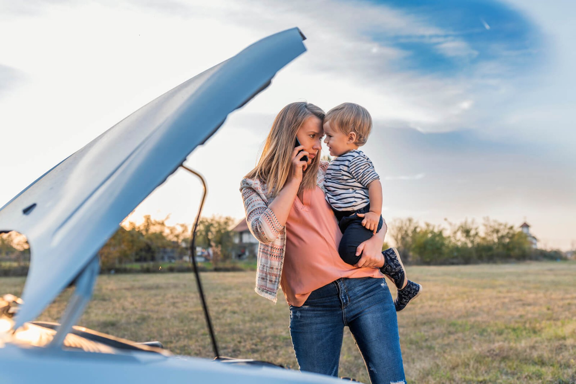 Woman with a child waiting safely beside a disabled car before a light duty tow